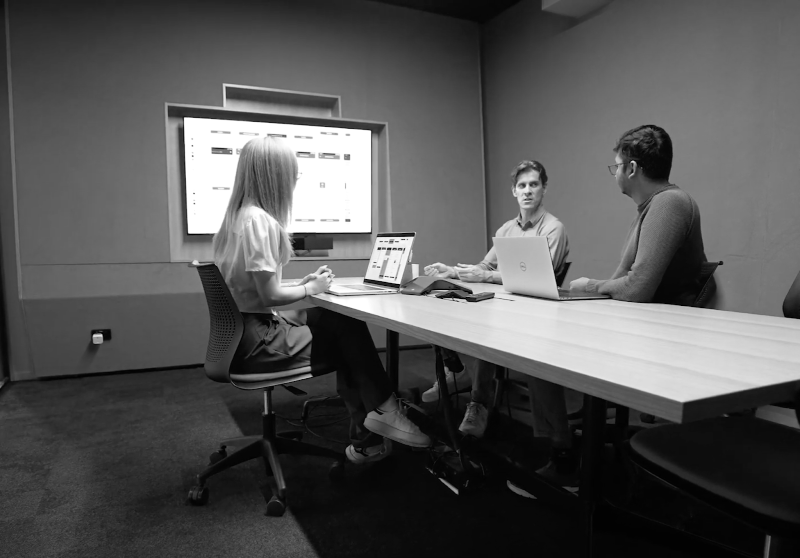 three people sat in a meeting room